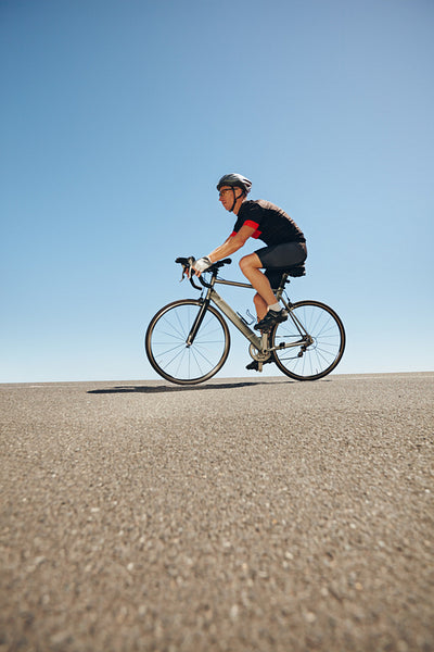 Male cyclist riding bicycle on flat road