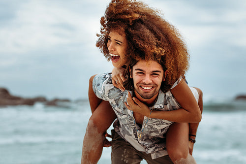Couple piggybacking at the beach