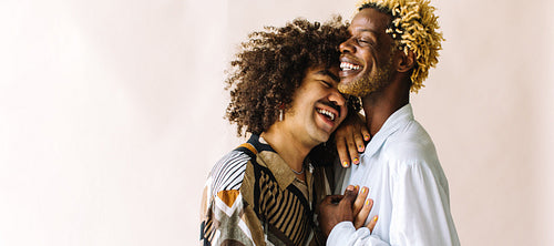 Happy young gay couple standing in a studio