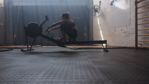 Sportswoman doing exercises with rowing machine