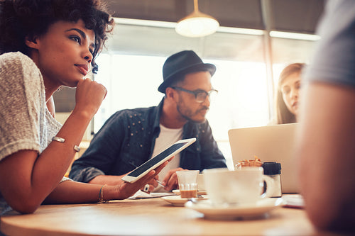 Young friends at a coffee shop with laptop and digital tablet