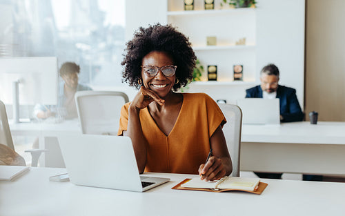 Modern business woman with glasses smiling and looking at camera in office