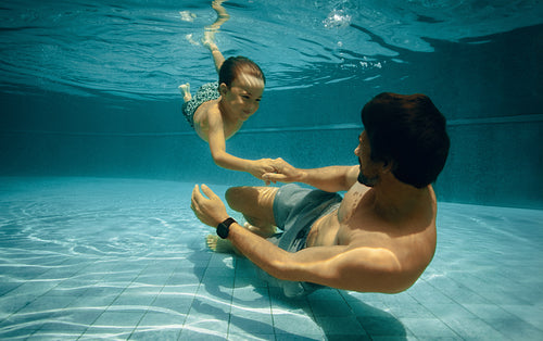 Father and son bonding underwater in swimming pool