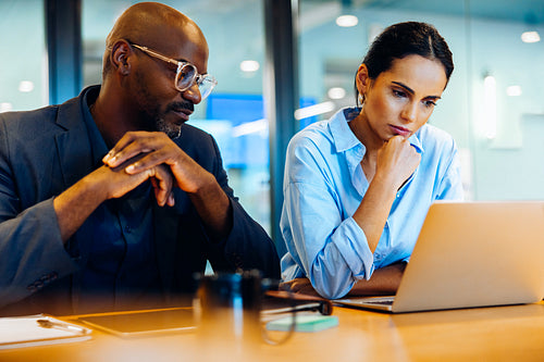 Two colleagues focused on a laptop during a thoughtful discussion