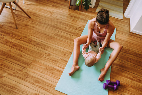Overhead view of a mom working out with her baby at home