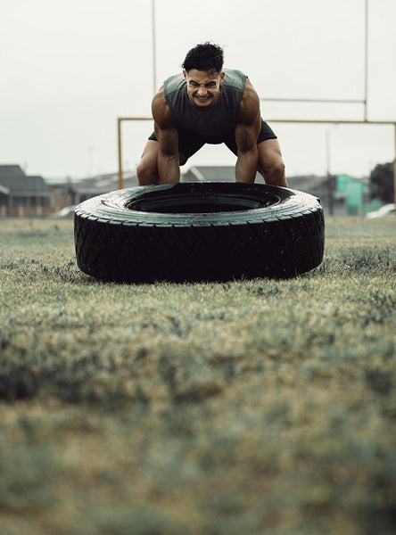 Muscular athlete doing a tire flip workout