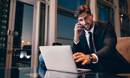 Businessman at airport waiting lounge using laptop and mobile phone