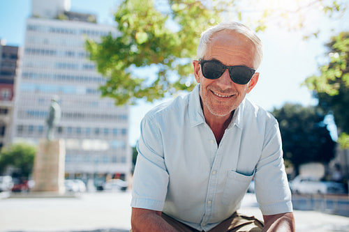 Happy senior man sitting outdoors in the city