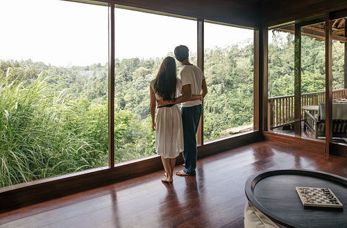 Couple standing by window and looking at landscape