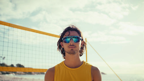 Static portrait shot of a determined male beach volleyball player wearing polarized sunglasses.