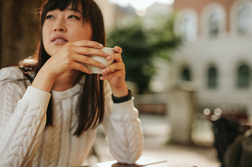 Chinese woman at outdoor cafe with cup of coffee