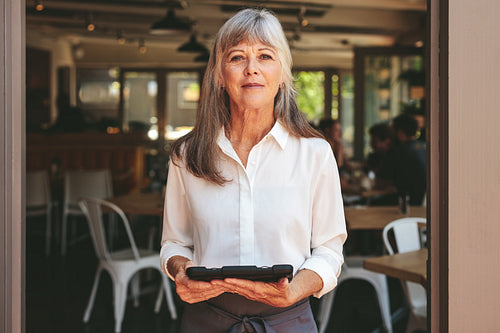 Female cafe owner standing at the entrance door