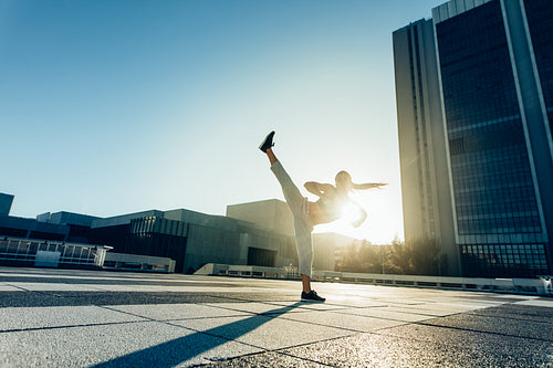 Urban woman doing high roundhouse kick