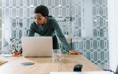 Businesswoman in boardroom making notes for meeting