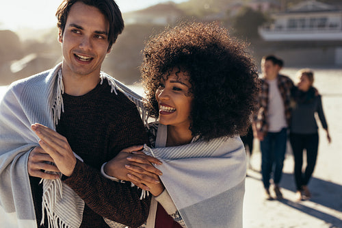 Smiling young couple walking on the beach