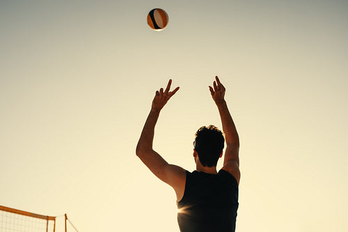 Sunset volleyball: Athlete signals setter with raised arms in pro tournament