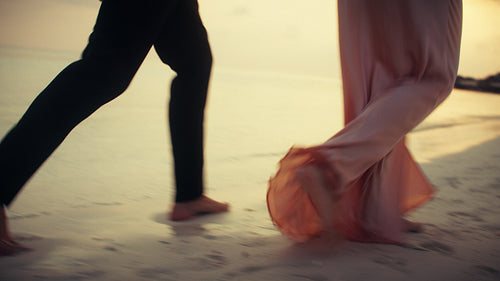 Couple walking hand in hand on a tropical beach at sunset during their luxury vacation