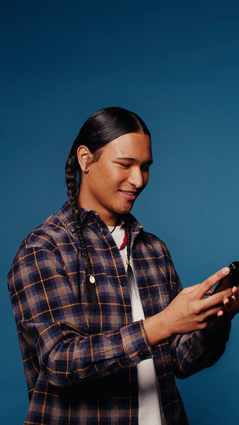 Young man using phone on blue background taking selfie, texting, scrolling