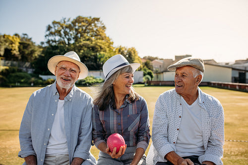 Senior friends sitting outdoors and laughing