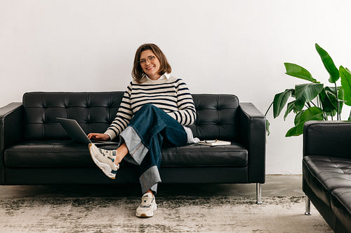 Woman working from home on a couch with laptop in a casual living room