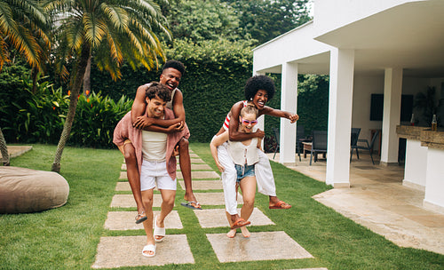 Family and friends enjoying piggyback rides in the yard