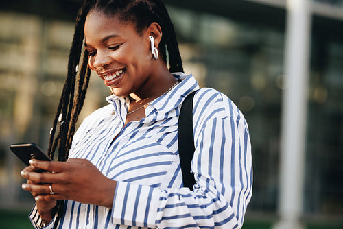 Cheerful young business woman using a smartphone while commuting in the city