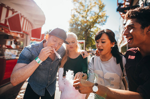 Young people sharing candyfloss at fairground