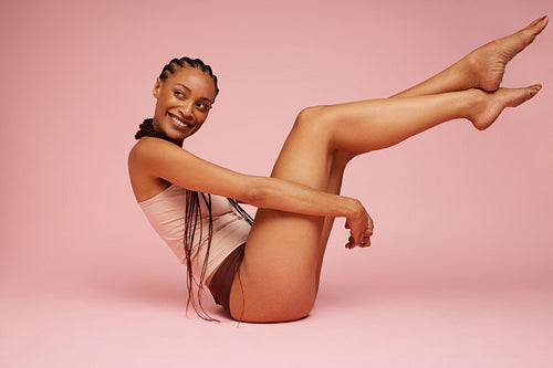Beautiful woman sitting on pink background