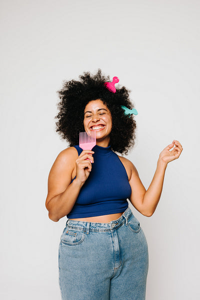Excited woman with Afro hair singing while holding a fork comb