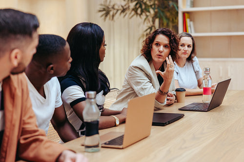 Female leader guiding a diverse team during a professional meeting session
