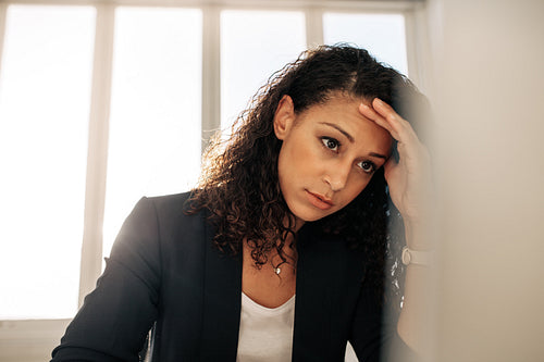 Woman entrepreneur sitting in office holding her head