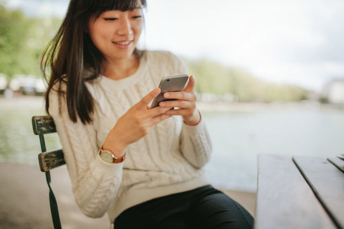 Happy young female using mobile phone at outdoor cafe