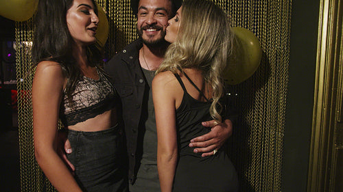 Man getting friendly kisses by party girls