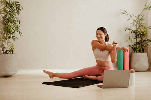 Woman stretching watching online video on laptop