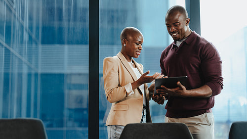 Business colleagues reviewing project on tablet in modern office setting