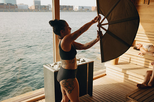 Sauna master performs wellness ritual with heat fan and relaxing guest