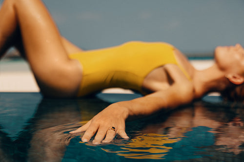 Woman relaxing by the pool in a yellow swimsuit