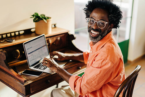 Cheerful Afro-Brazilian freelancer happily working from home on a laptop