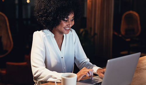 Happy young woman working late in office