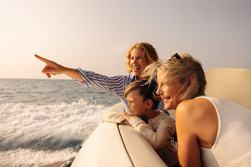 Mother, son, and grandmother enjoying a boat ride on a sunny day