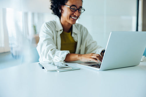 Woman types on laptop at clean desk
