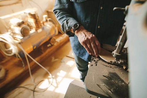 Carpenter cuts and shapes the wood using band saw