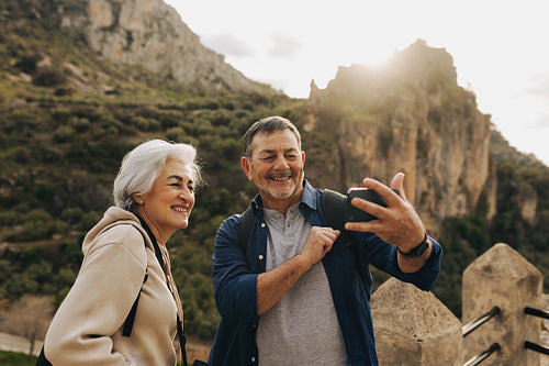 Elderly couple having a video call while hiking outdoors