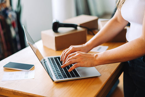 Female online store owner using a laptop in her shop