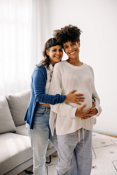 Expectant lesbian couple smiling at the camera