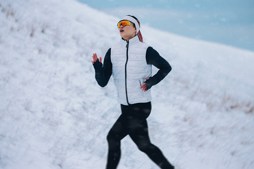 The athlete running through snow gives the woman a strong winter training moment