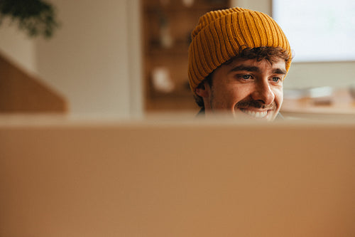 Smiling creator works at home behind a computer screen
