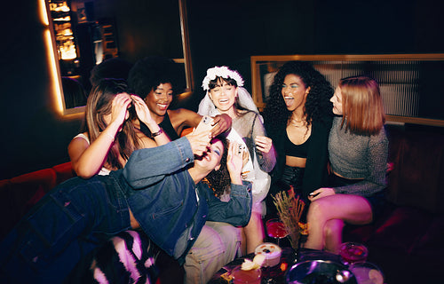 Group of women celebrating a joyful occasion with laughter and drinks