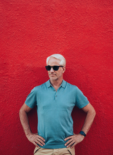 Stylish mature man posing against red wall