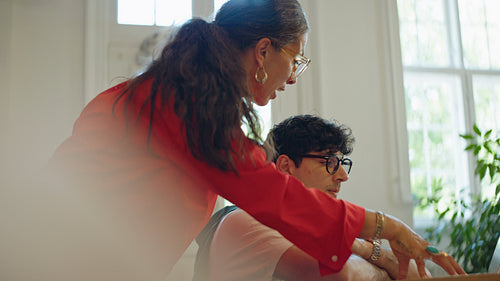 Woman guides a coworker at the laptop during business training